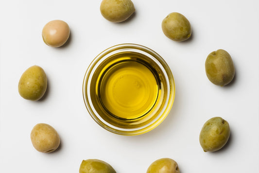 Golden olive oil poured into a small glass bowl.